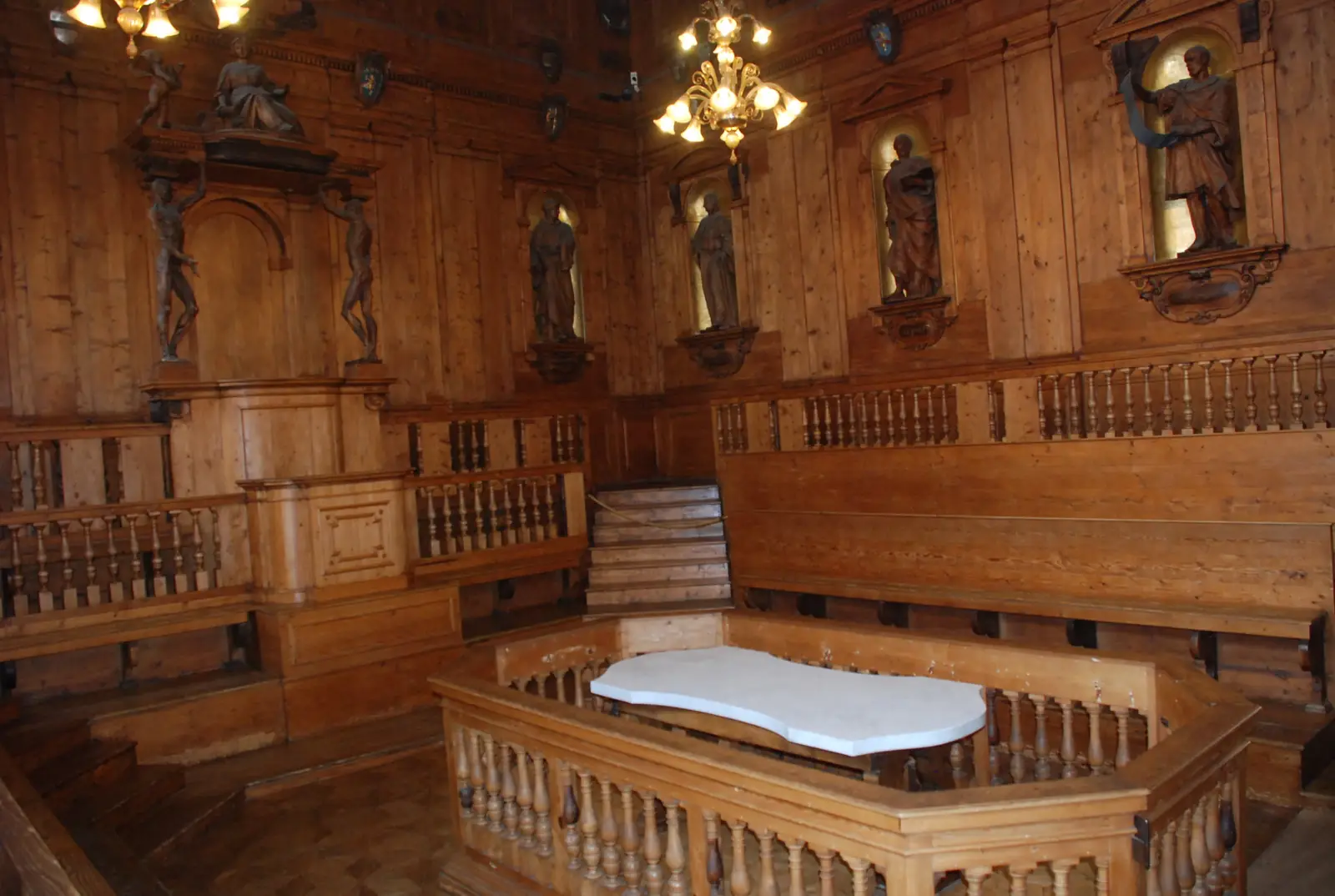 The empty wood-panelled Teatro Anatomico inside the Archiginnasio, with carved statues around the walls and a white dissection table in the middle