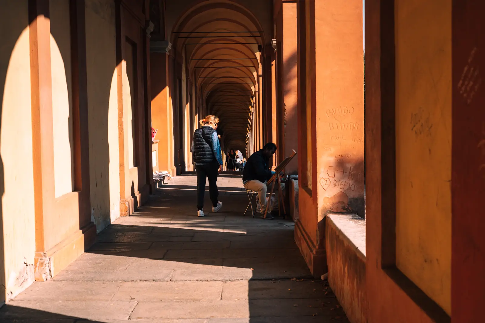 A long covered portico walkway in Bologna lit by golden light
