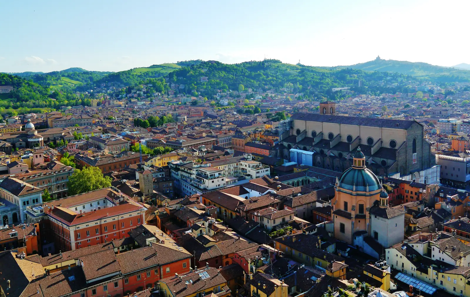 View from the Asinelli tower over Bologna's red rooftops to the Basilica di San Petronio and the green hills beyond