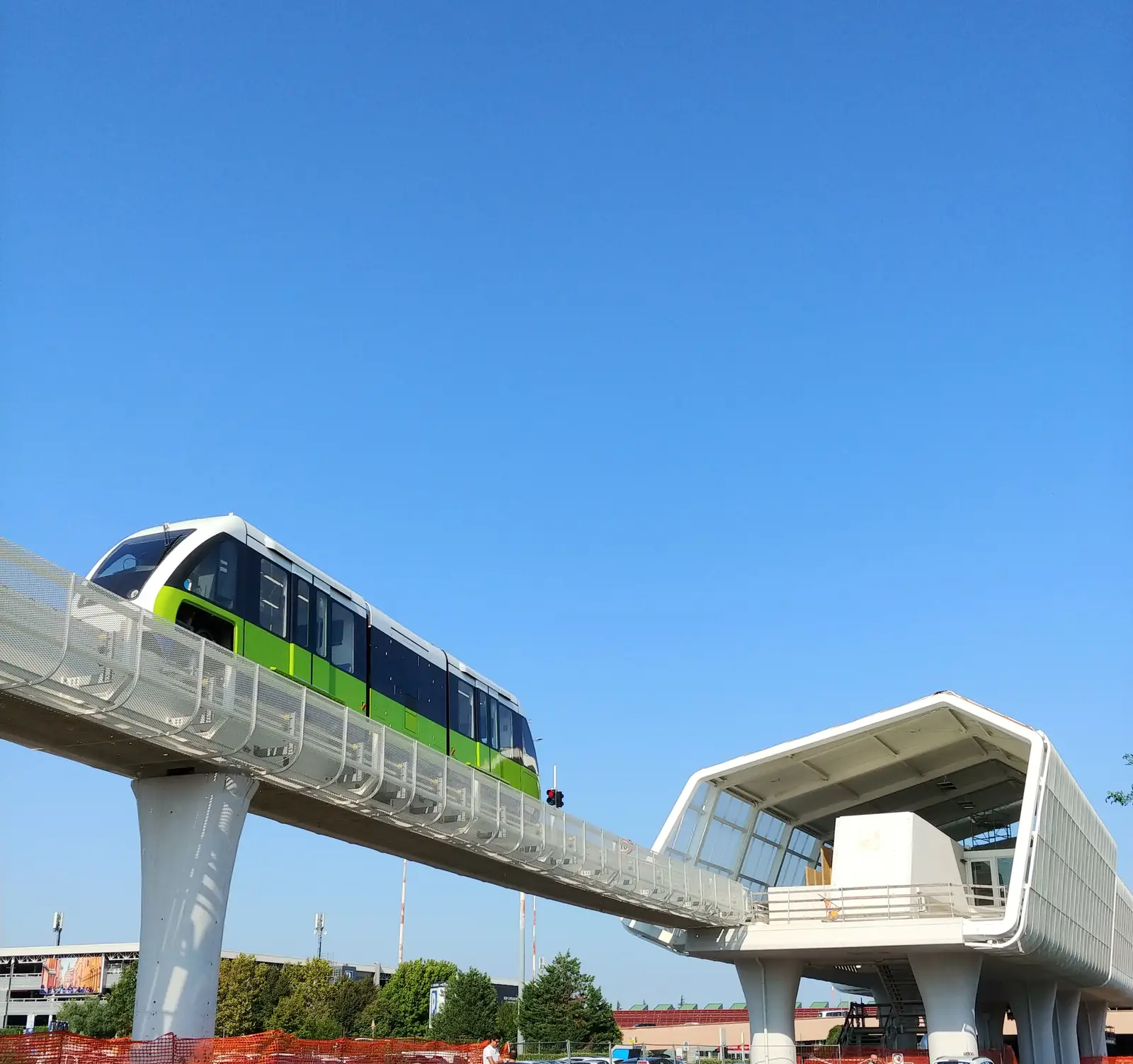 A green and white Marconi Express monorail car on its elevated track beside the airport station