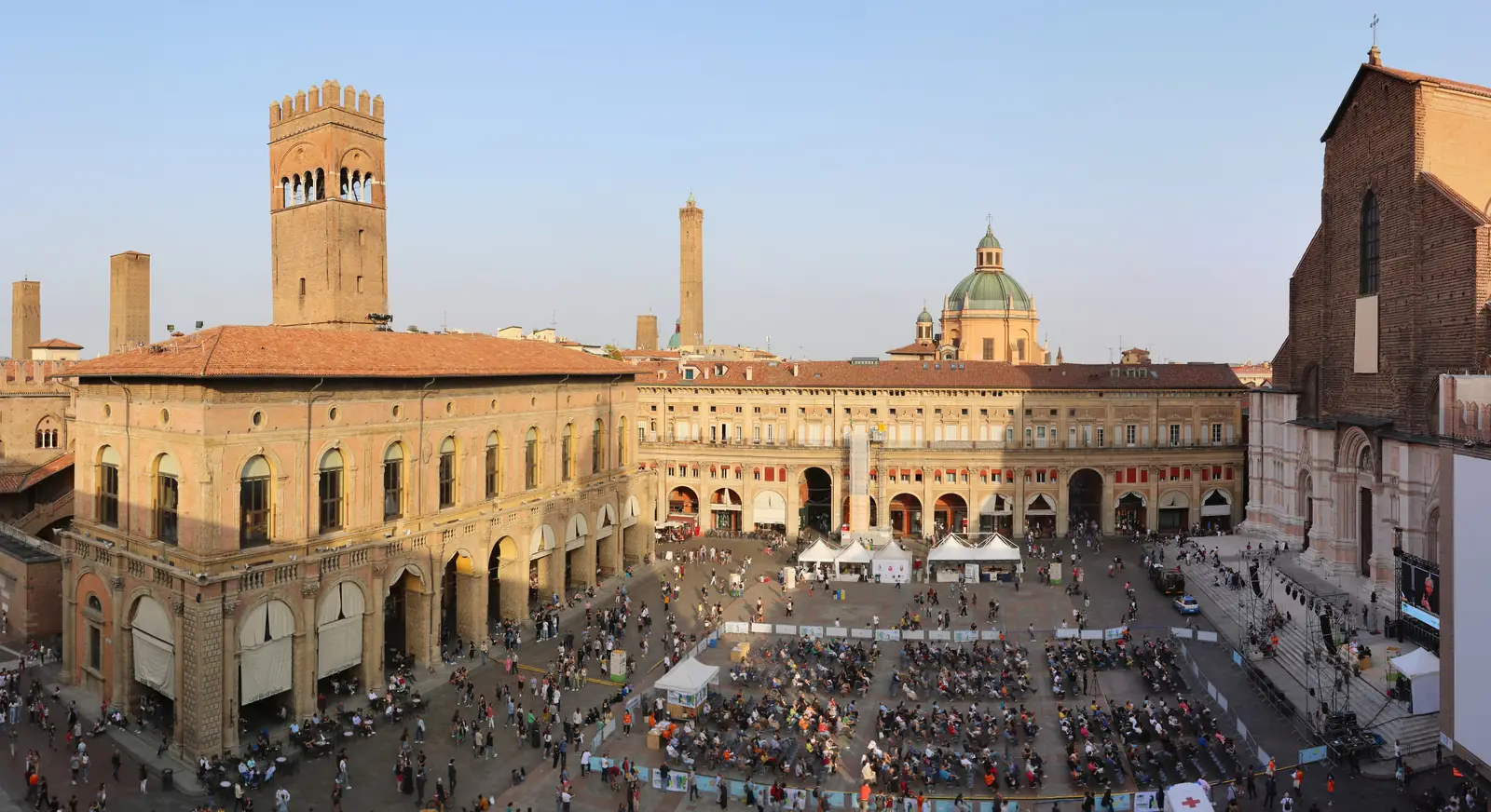 Piazza Maggiore in Bologna at golden hour, seen from above, with the Basilica di San Petronio and Palazzo Re Enzo around the open square