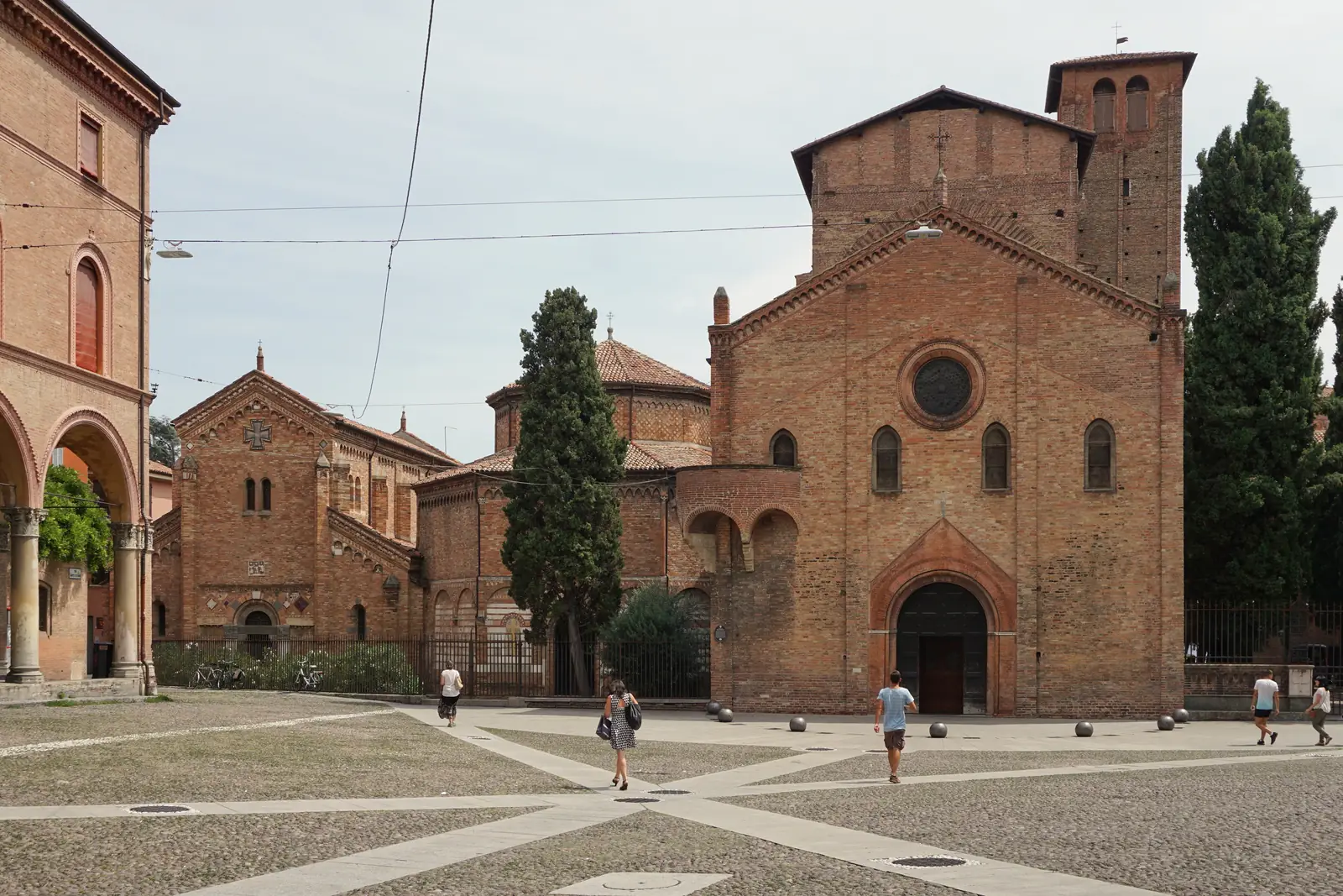 Piazza Santo Stefano in Bologna with the brick churches of the Santo Stefano complex and two tall cypress trees