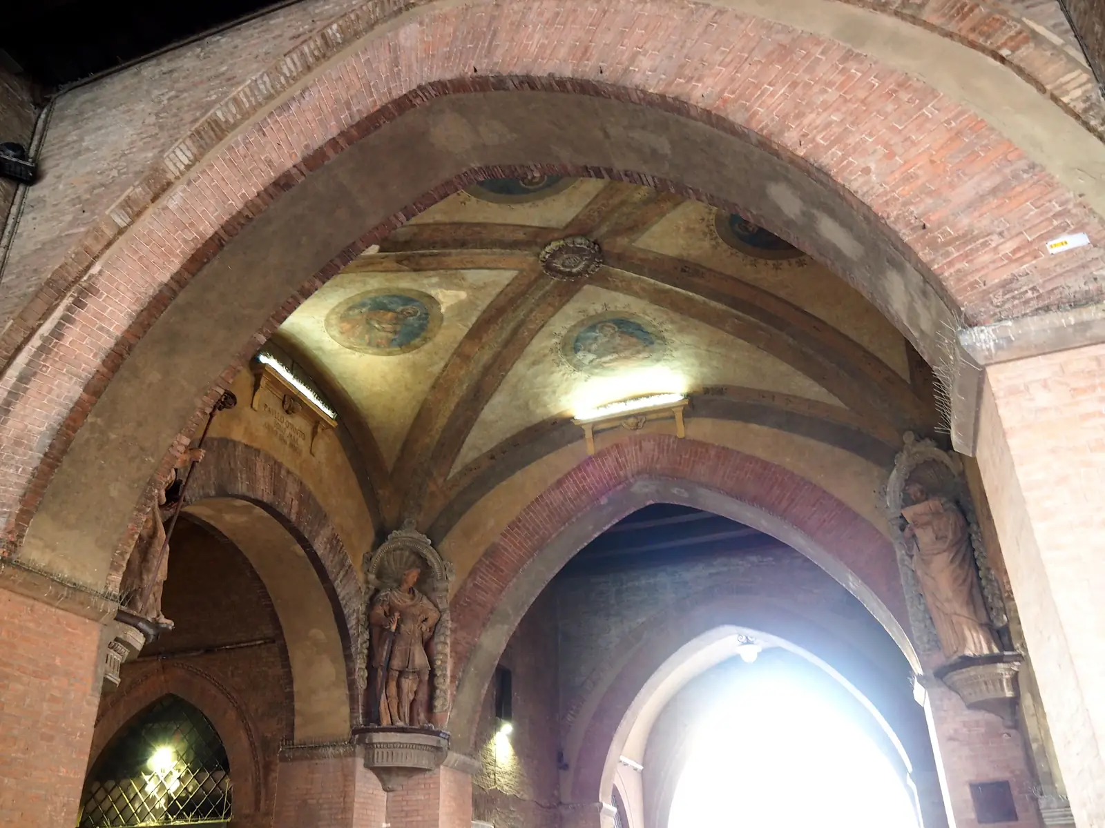 The vaulted crossing of the Voltone del Podestà with terracotta statues of Bologna’s patron saints